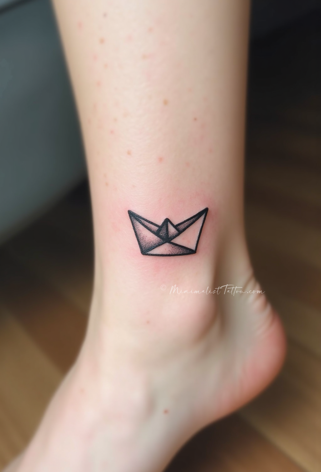 Minimalist origami boat ankle tattoo